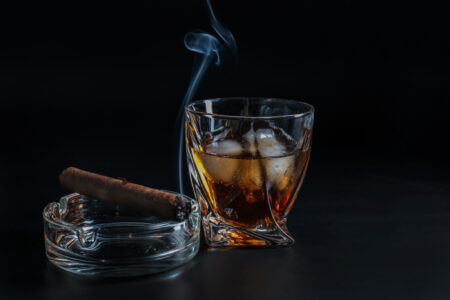 Glass Of Cold Whiskey With Cigar On Dark Background Glass Of Cold Whiskey With Cigar On Dark Background